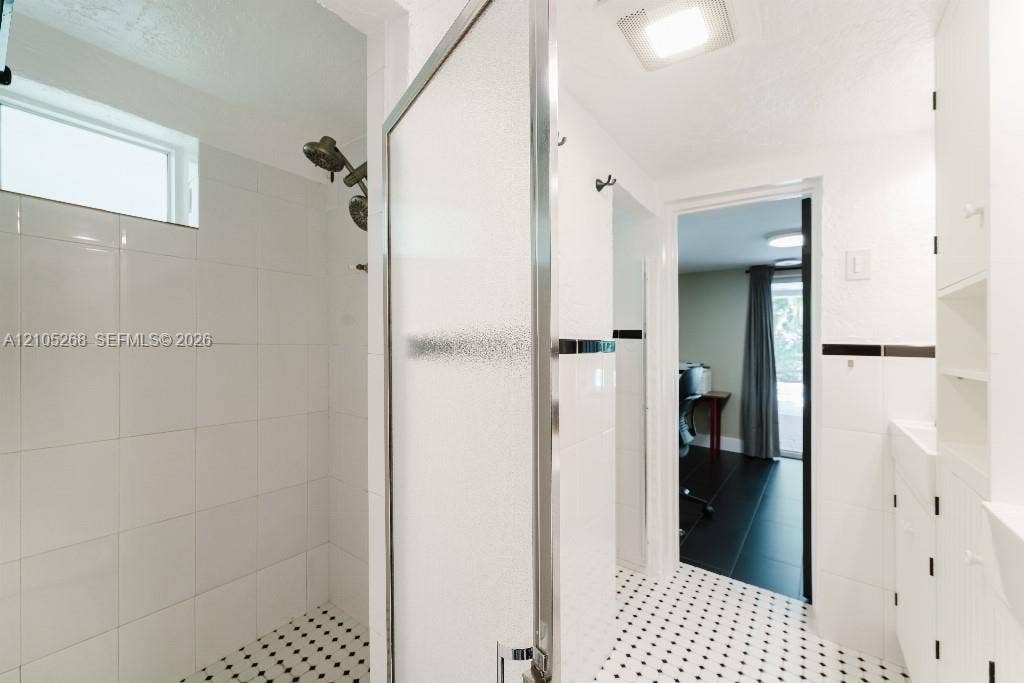 230 Miami Springs Avenue, Miami Springs, FL 33166 Shower enclosure with a satin nickel shower head, white subway tile surround, and mosaic tile flooring