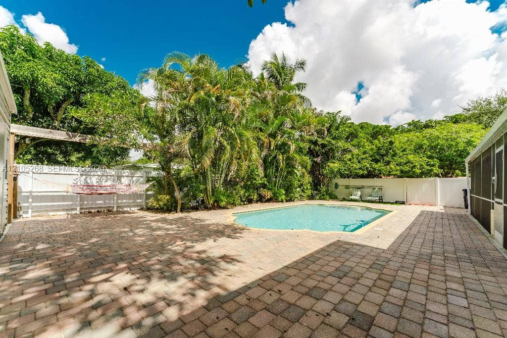 230 Miami Springs Avenue, Miami Springs, FL 33166 Outdoor swimming pool with a paver patio and mature tropical landscaping