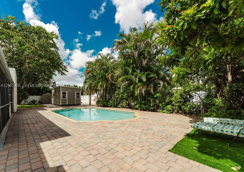 230 Miami Springs Avenue, Miami Springs, FL 33166 Paved patio with an in-ground pool, surrounded by mature trees and lush landscaping