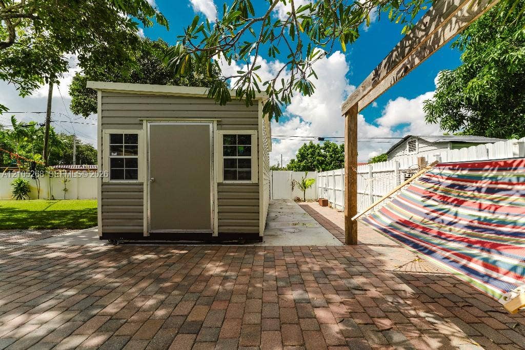 230 Miami Springs Avenue, Miami Springs, FL 33166 Brick paver patio, wood-beam pergola, and a storage shed with siding and windows