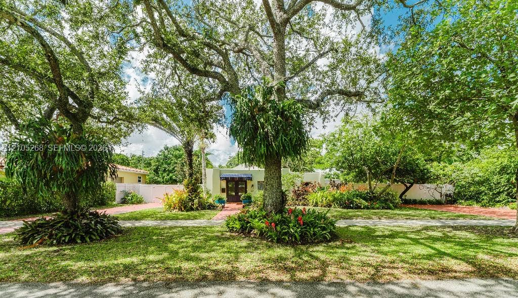 230 Miami Springs Avenue, Miami Springs, FL 33166 Expansive front yard featuring mature trees, manicured lawn, and lush landscaping