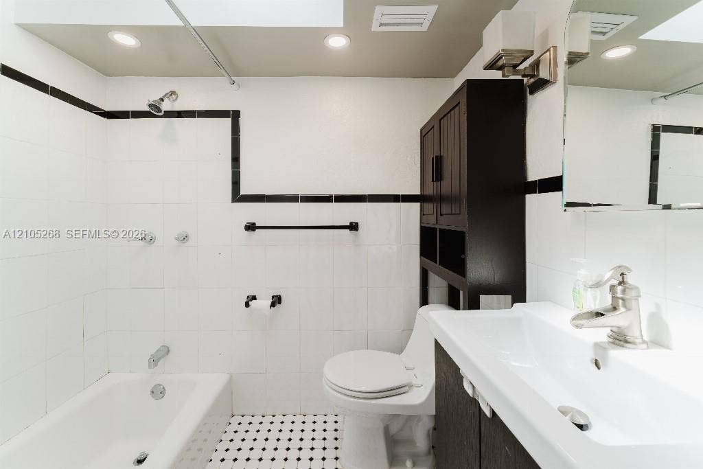 230 Miami Springs Avenue, Miami Springs, FL 33166 White subway tile with black trim, recessed lighting, black and white mosaic floor tile, white vanity with integrated sink, and dark wood-finish cabinet