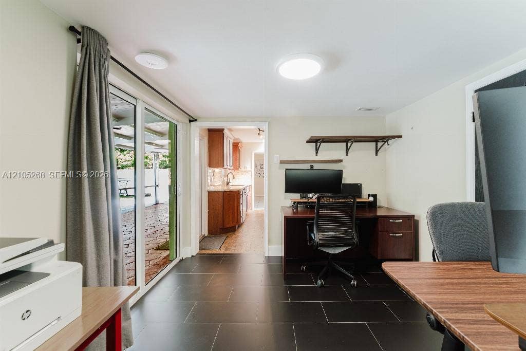 230 Miami Springs Avenue, Miami Springs, FL 33166 Black tile flooring, sliding glass door, built-in shelving, recessed ceiling lighting, and a doorway opening to a kitchen