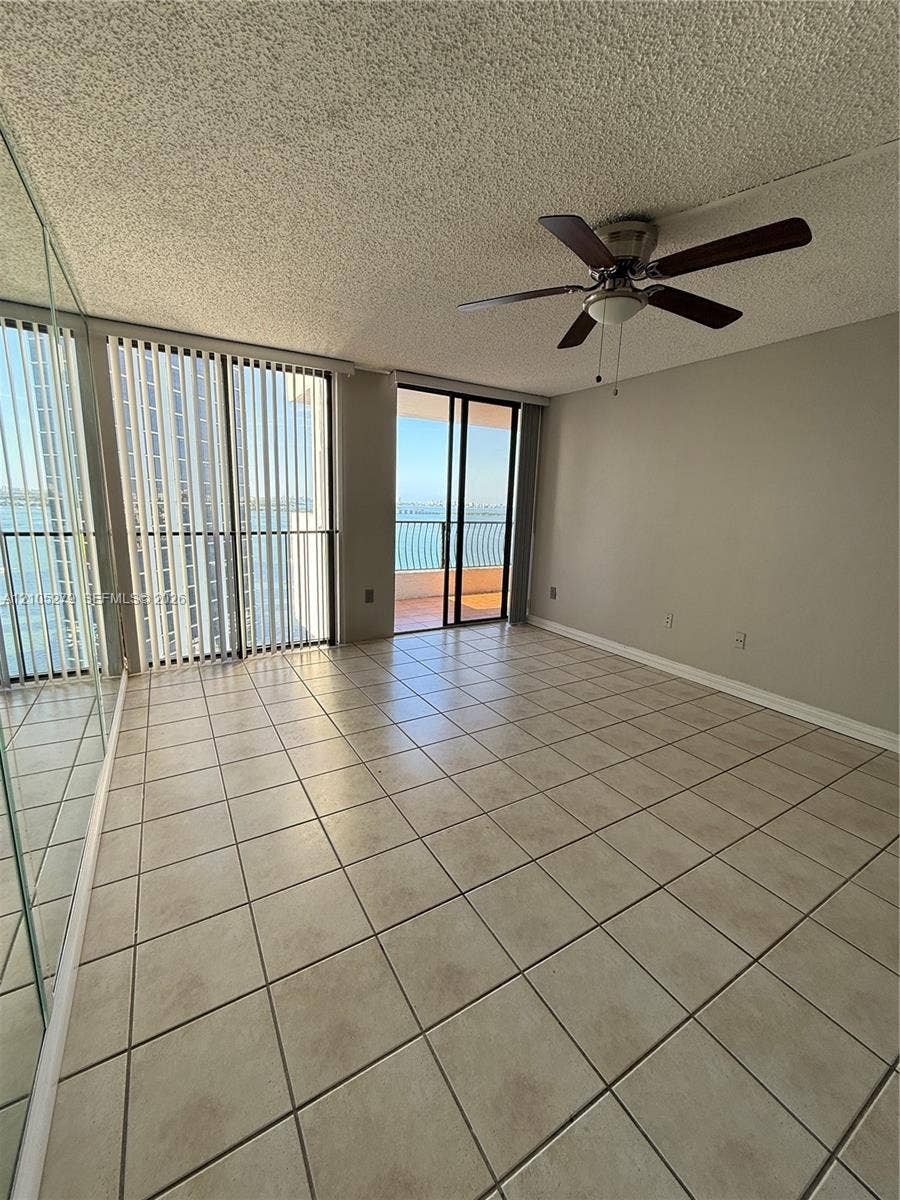 Tile flooring throughout, full-length mirrored wall, ceiling fan with integrated lighting, and sliding glass doors to outdoor area