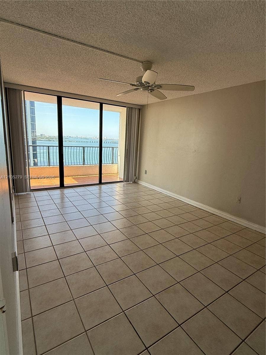 Tile flooring, expansive glass sliding doors, private balcony, ceiling fan with light fixture, neutral wall finishes