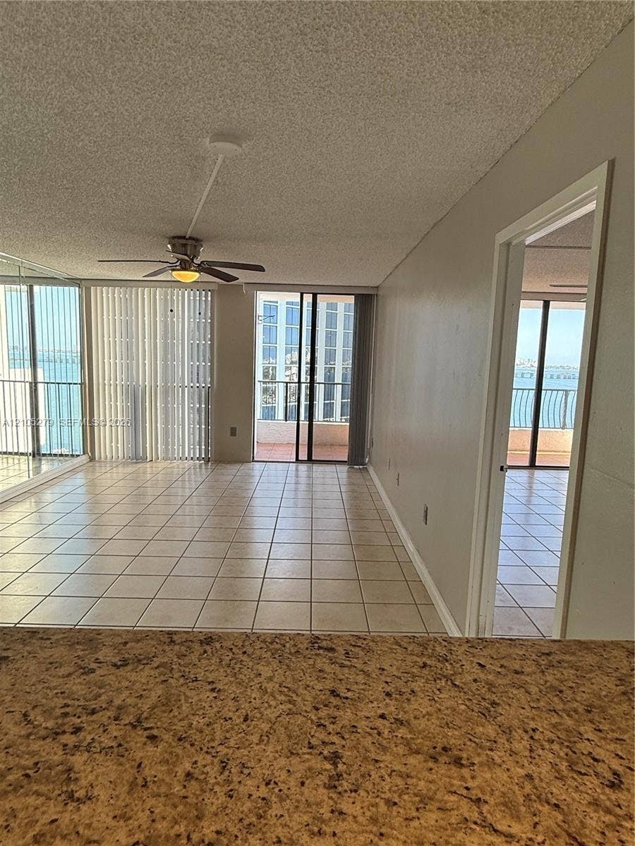 Tile flooring throughout, with a ceiling fan in the living area, and an exterior balcony