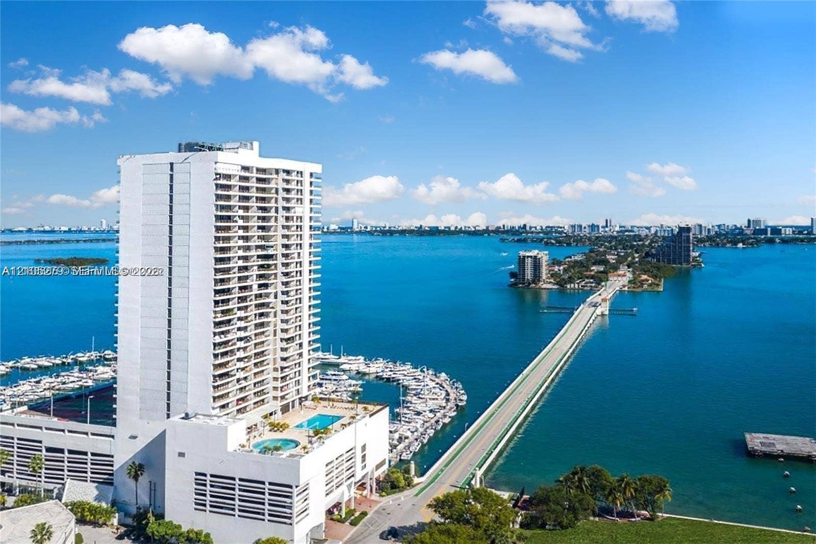High-rise building with extensive balconies, multi-level parking structure, and rooftop pool