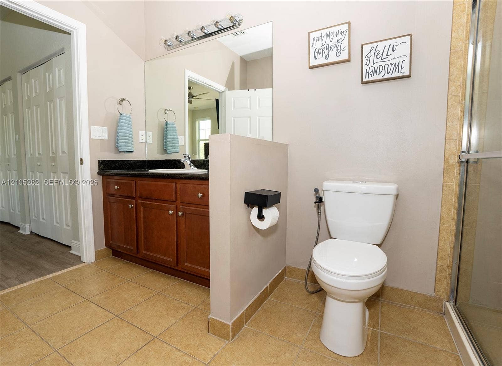 1104 SW 146th Terrace, Pembroke Pines, FL 33027 Bathroom featuring wood-finish cabinetry, dark stone-surfaced vanity top, large wall-mounted mirror, multi-bulb light fixture, and tile flooring