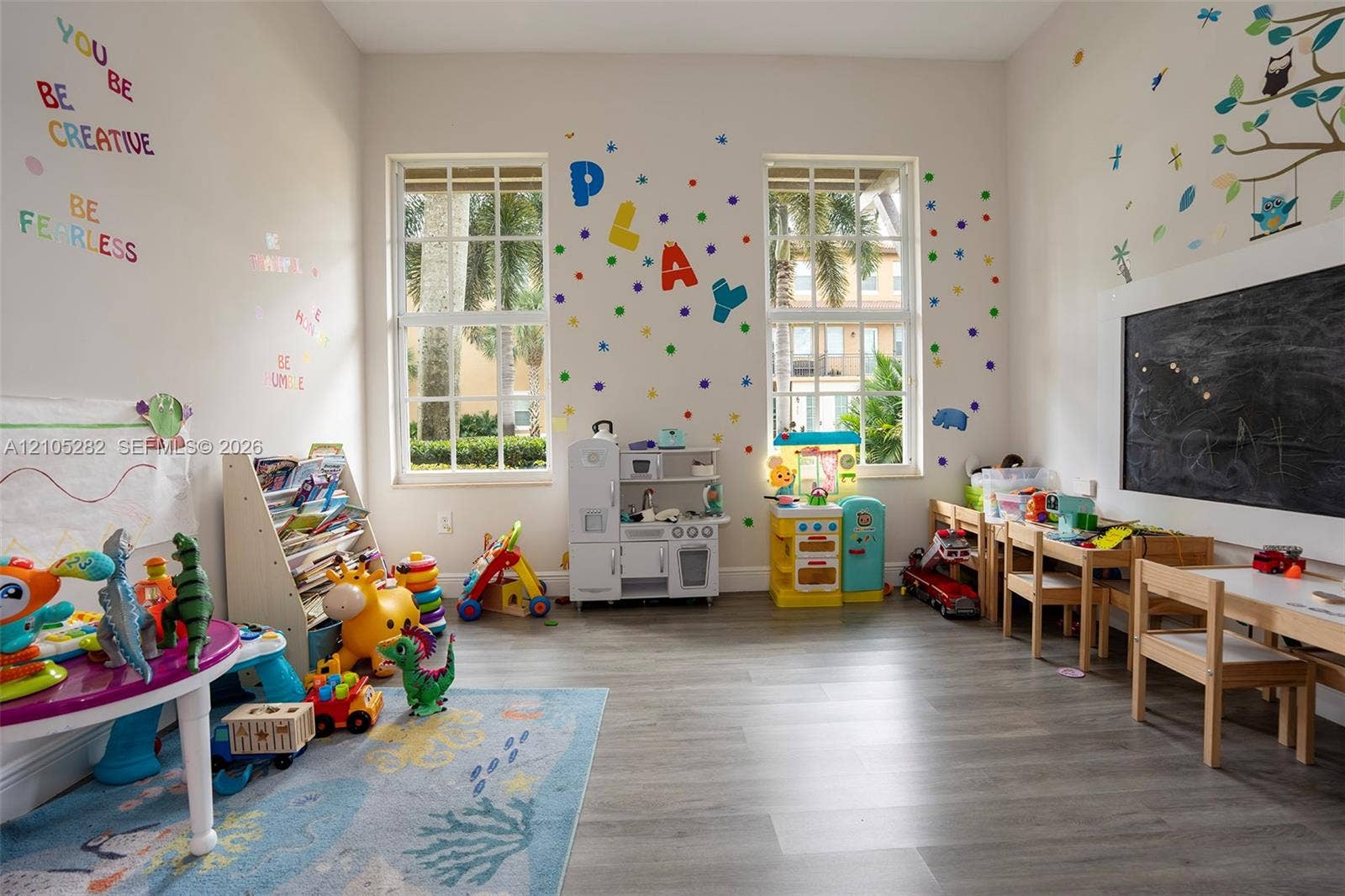1104 SW 146th Terrace, Pembroke Pines, FL 33027 Room featuring high ceilings, wood-finish flooring, two large multi-pane windows, and a built-in chalkboard