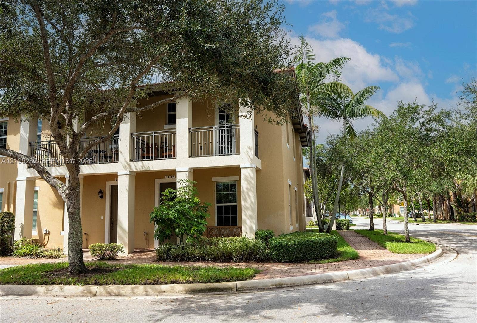 1104 SW 146th Terrace, Pembroke Pines, FL 33027 Two-story exterior featuring a stucco facade, covered ground-floor patio, second-level balcony with metal railings, and a paver walkway