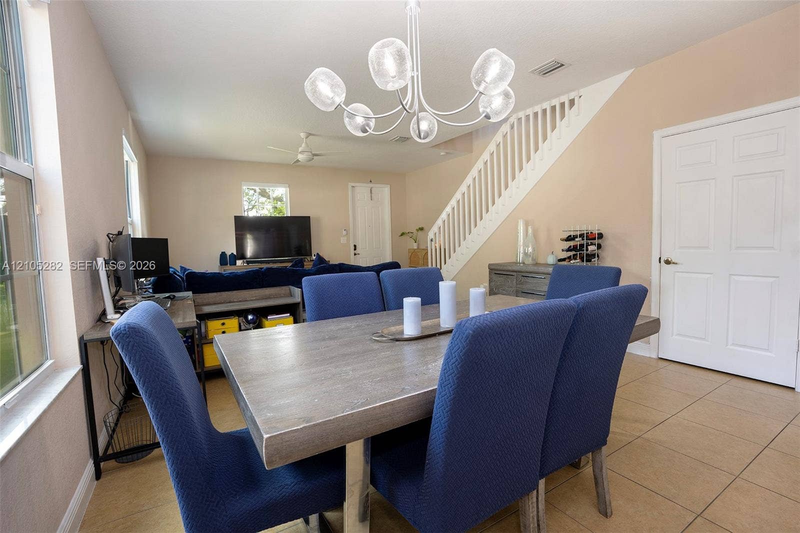 1104 SW 146th Terrace, Pembroke Pines, FL 33027 Open-concept area featuring tile flooring, a multi-arm orb chandelier, and a white wooden staircase with balustrades
