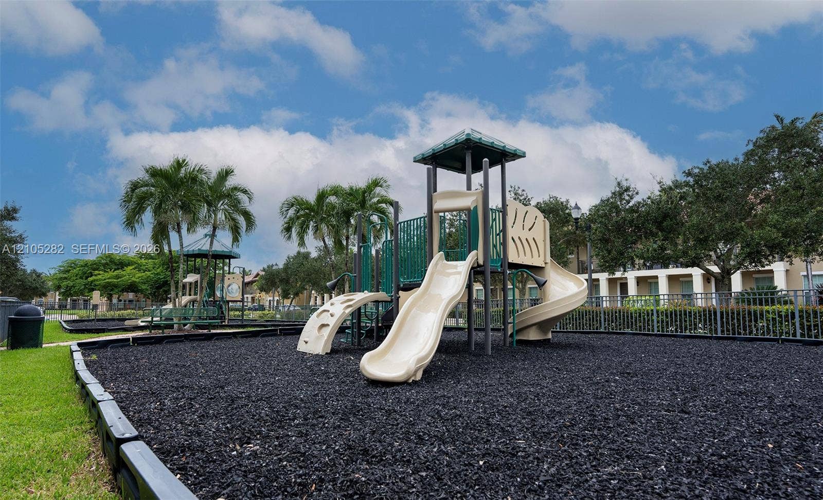 1104 SW 146th Terrace, Pembroke Pines, FL 33027 Recreational area featuring a multi-level climbing structure with slides, black rubber mulch surfacing, and metal perimeter fencing