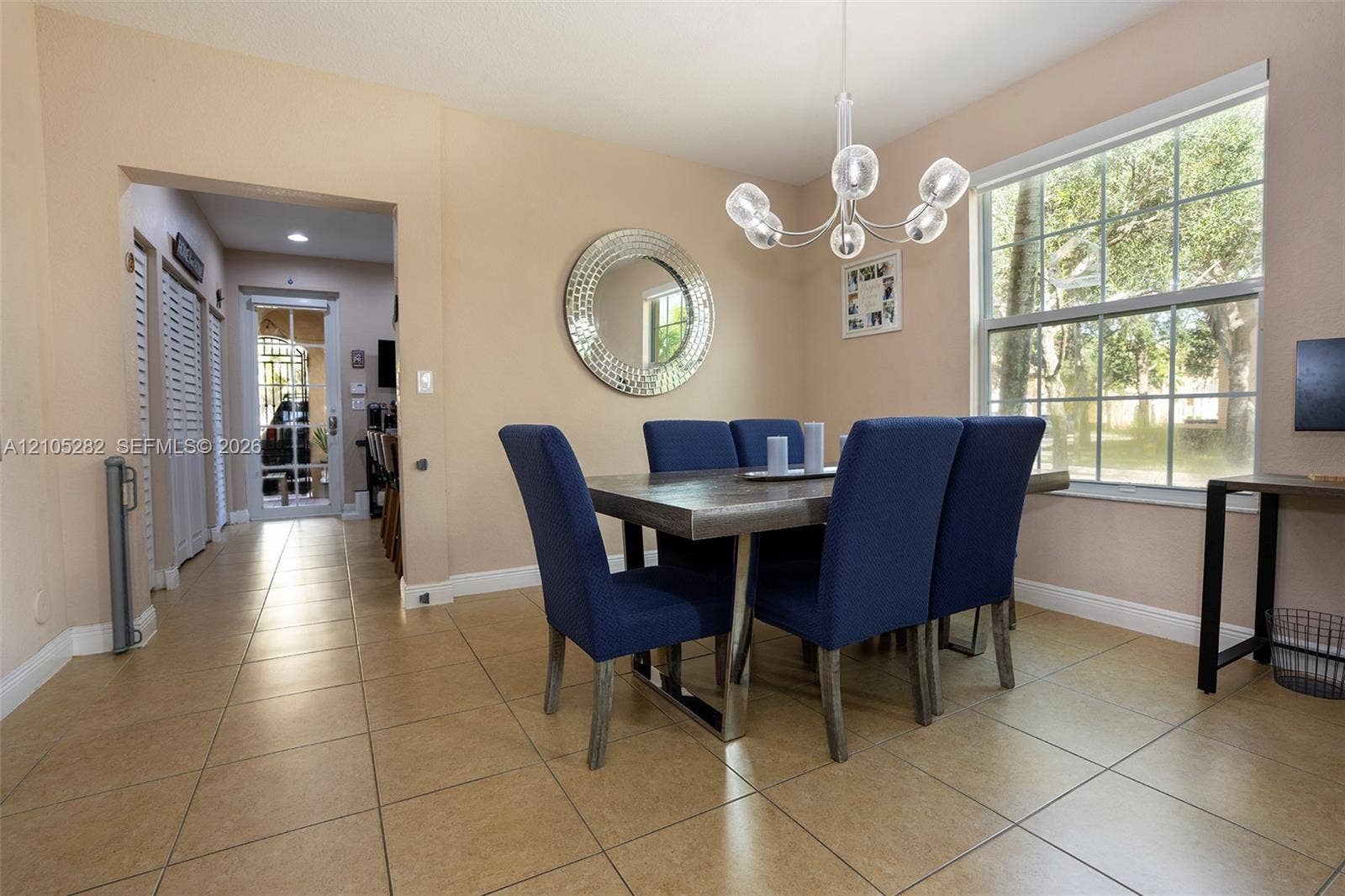 1104 SW 146th Terrace, Pembroke Pines, FL 33027 Dining area featuring large-format tile flooring, multi-globe chandelier, double-hung window, and louvered-style closet doors