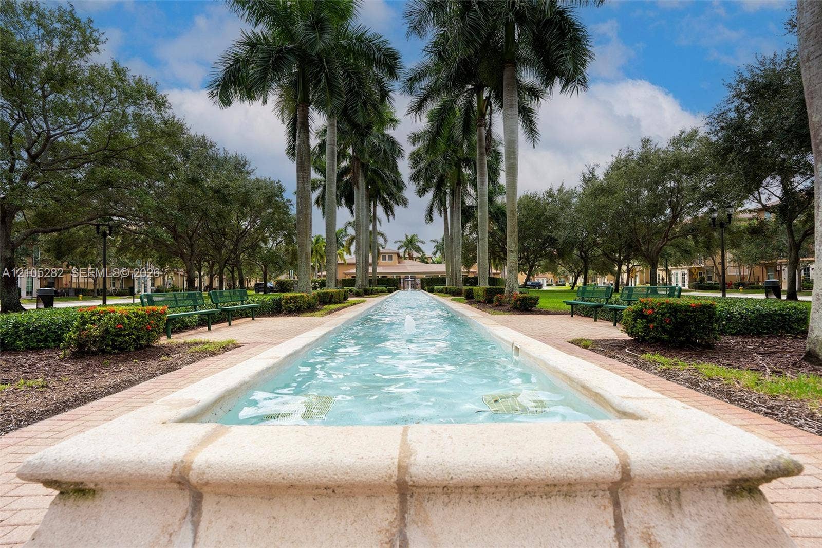 1104 SW 146th Terrace, Pembroke Pines, FL 33027 Linear water feature with stone coping, lined by mature palm trees, manicured hedges, and paver pathways