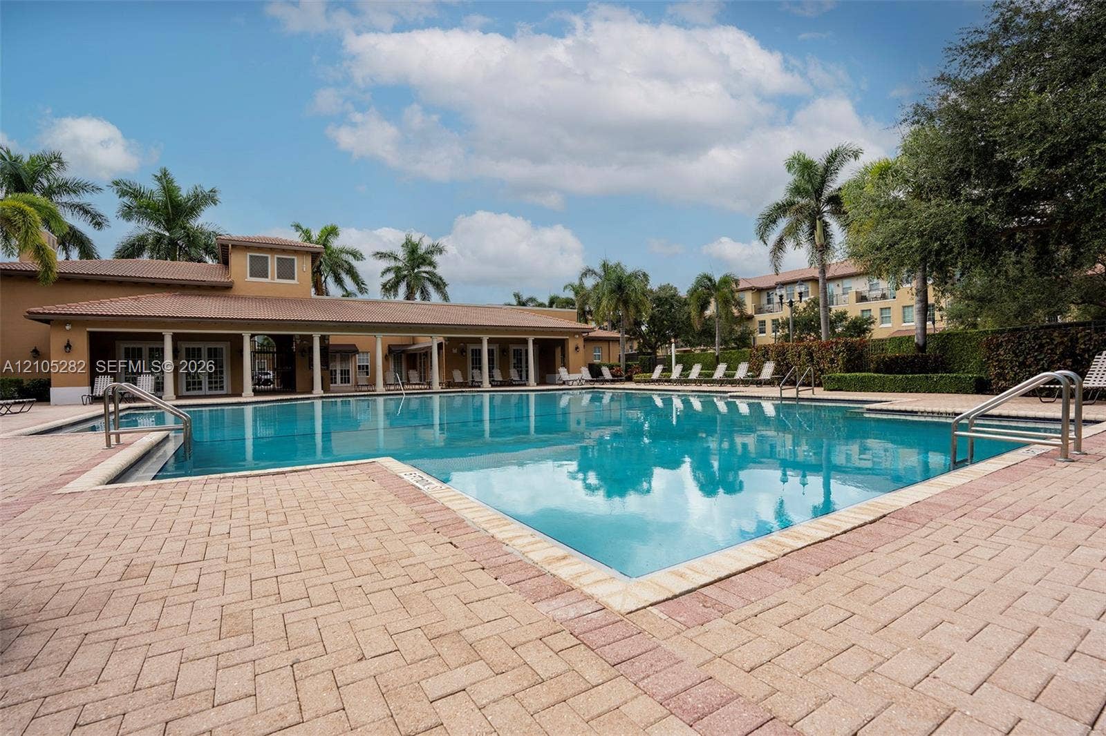 1104 SW 146th Terrace, Pembroke Pines, FL 33027 Outdoor swimming pool featuring a brick-paved deck, covered veranda with structural columns, and surrounding palm trees