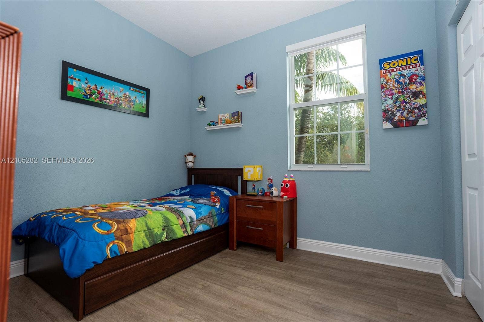 1104 SW 146th Terrace, Pembroke Pines, FL 33027 Wood-finish flooring, multi-pane window with white casing, and wall-mounted shelving