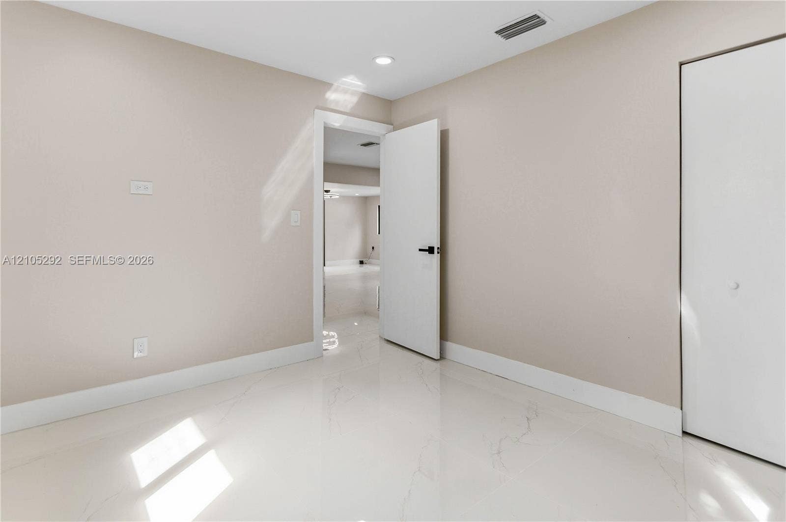 Polished light-toned flooring, neutral wall tones, recessed lighting, and a white door with dark hardware
