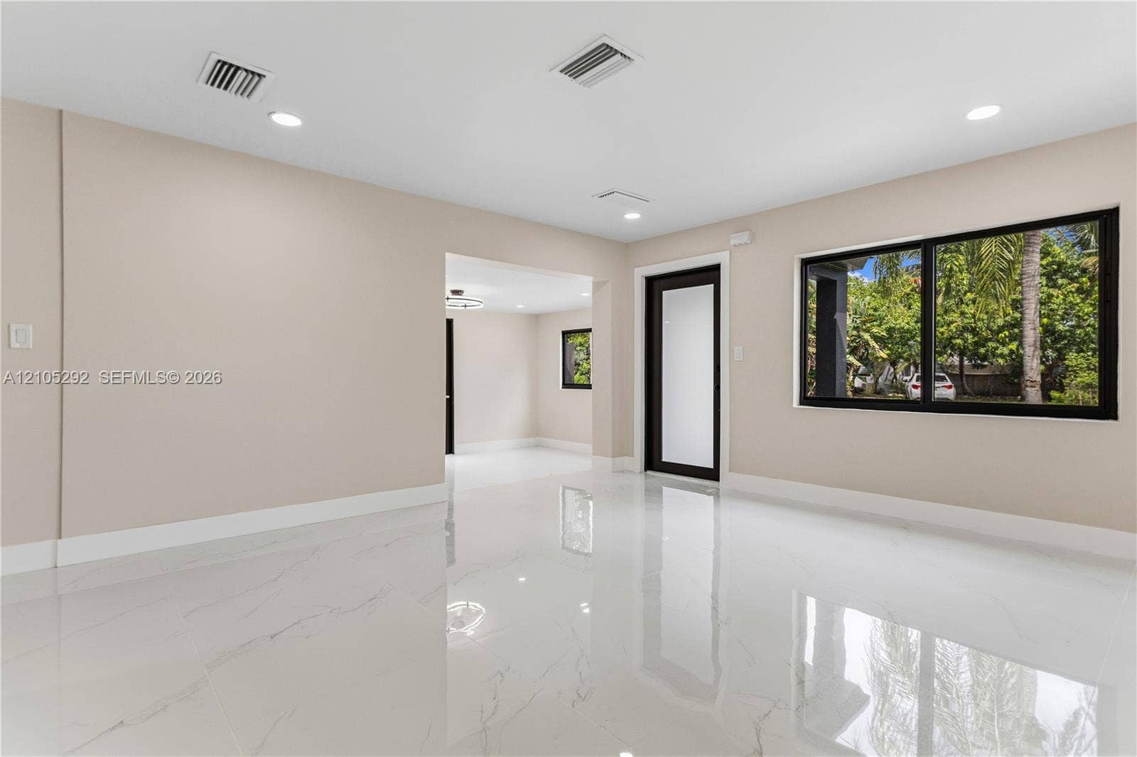 Polished tile flooring, recessed ceiling lighting, light-toned walls, and black-framed windows