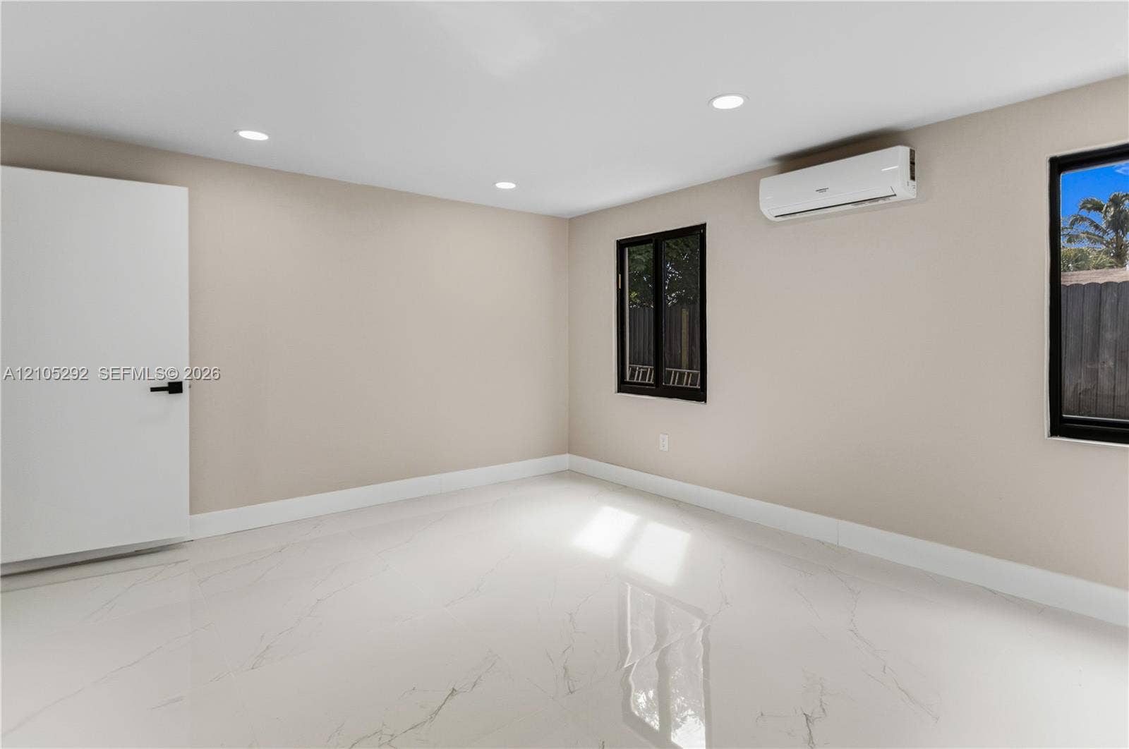 Recessed ceiling lighting, white tile flooring, mini-split air conditioning unit, white interior door with black hardware, and black-framed windows