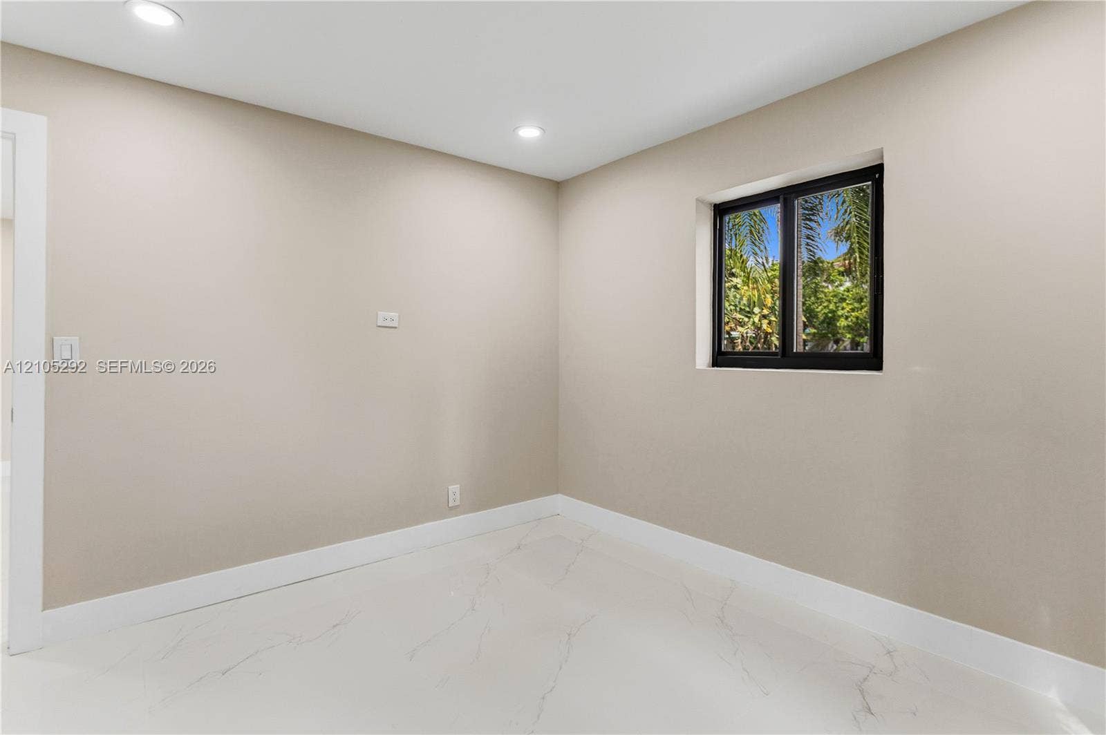 Recessed lighting, light neutral wall paint, white trim, white marble-look flooring, and a black-framed window