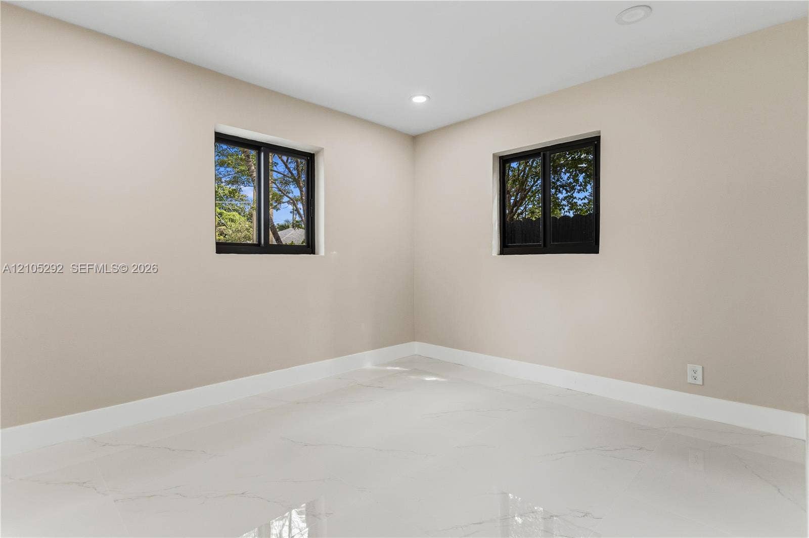 Smooth walls with a neutral finish, recessed lighting, white baseboards, and two windows with black frames