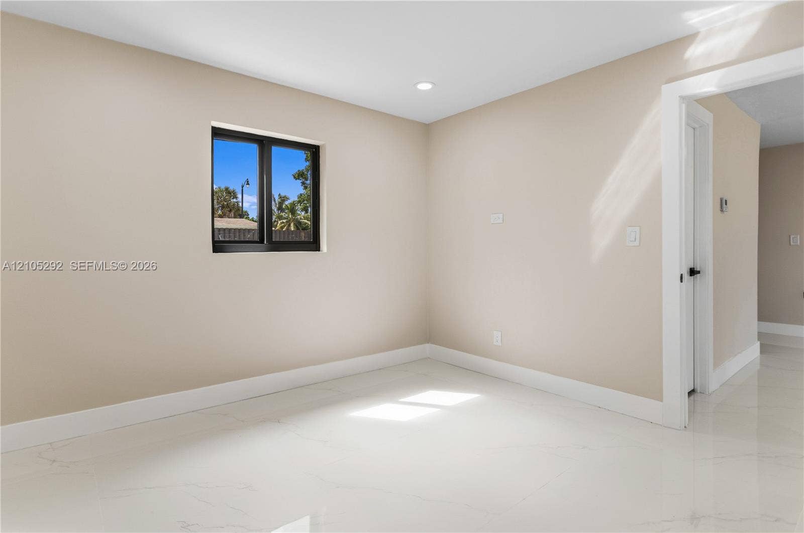 Recessed lighting, light neutral wall color, white floor tile, black framed window, white trim