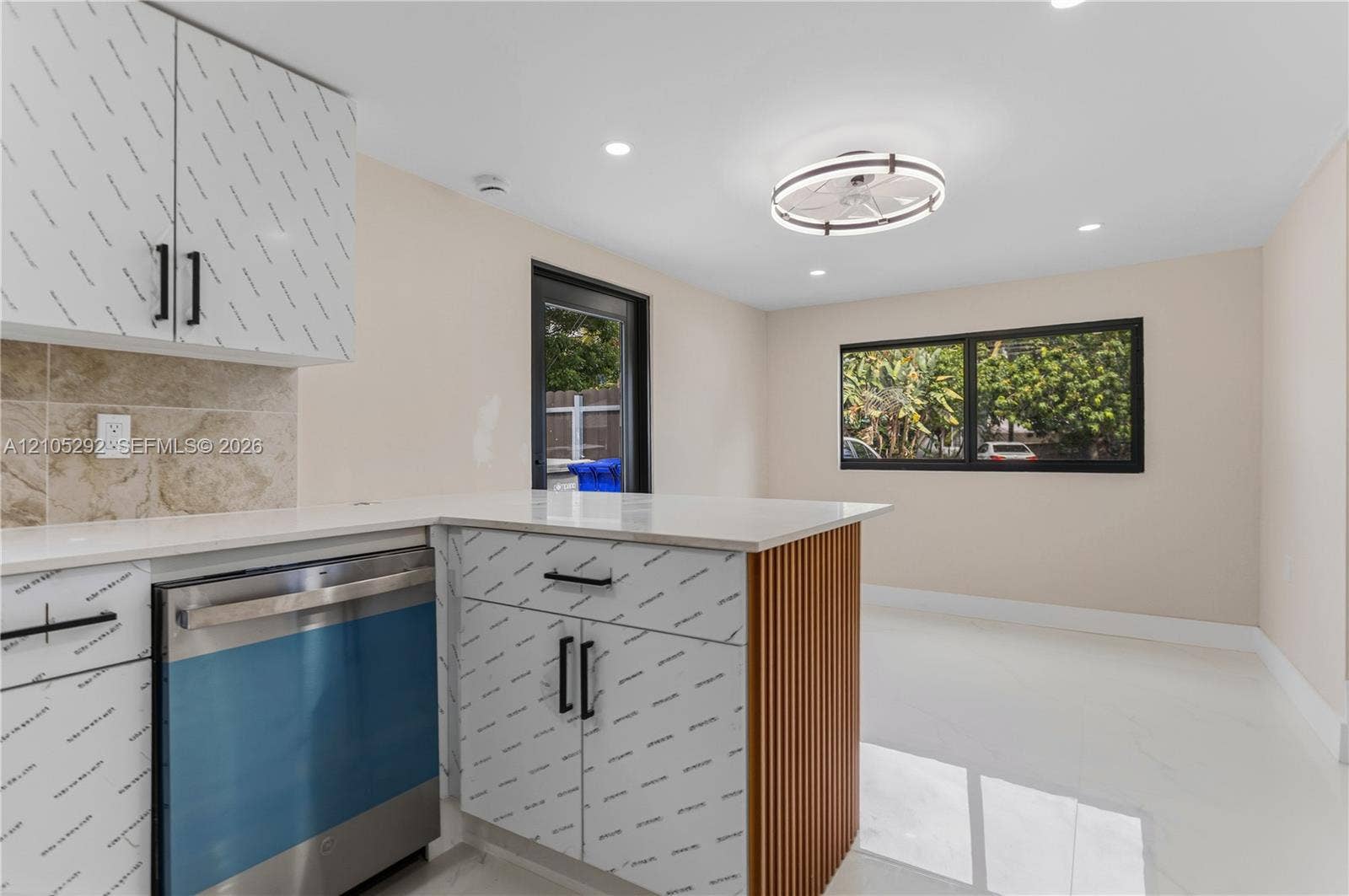 Kitchen with a white countertop island featuring a wood-finish slatted side panel, recessed lighting, and a stainless steel dishwasher