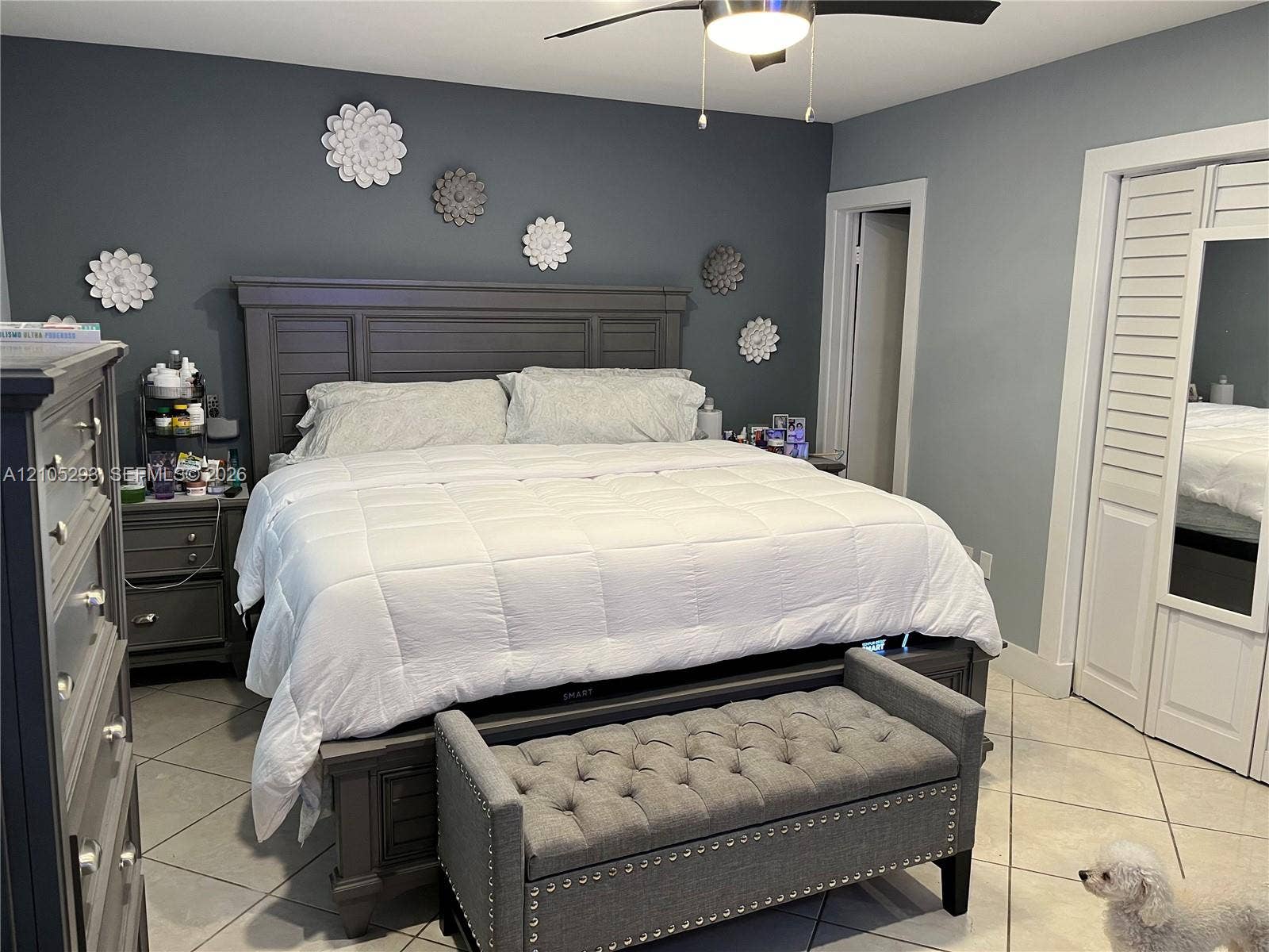3792 NE 167th Street, #50, North Miami Beach, FL 33160 Large-format tile flooring, louvered closet doors with integrated mirror, and a ceiling-mounted light fixture with fan