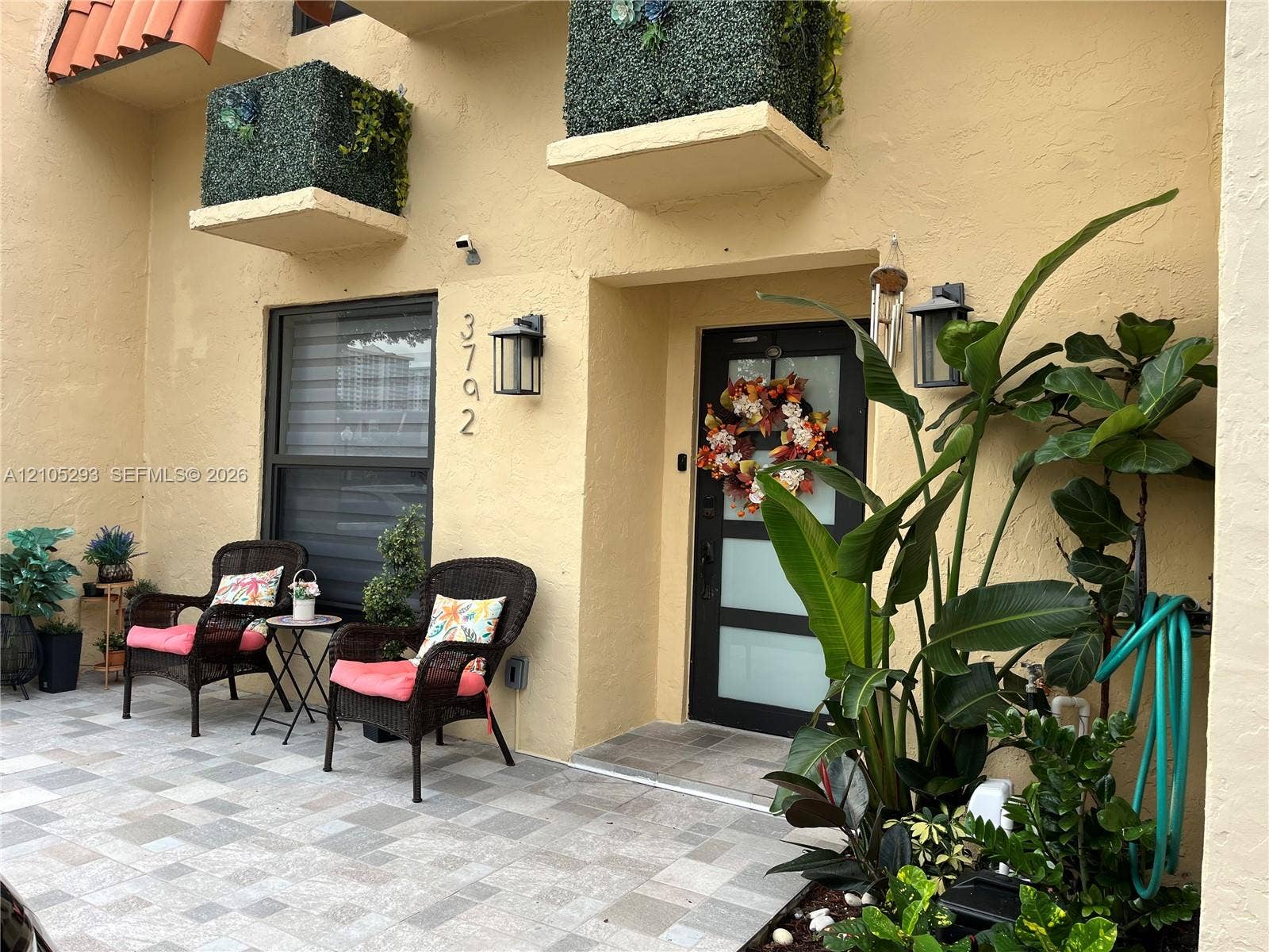 3792 NE 167th Street, #50, North Miami Beach, FL 33160 Exterior entrance featuring a tiled patio, stucco facade, integrated wall-mounted exterior lighting, and a modern entry door with frosted glass panels