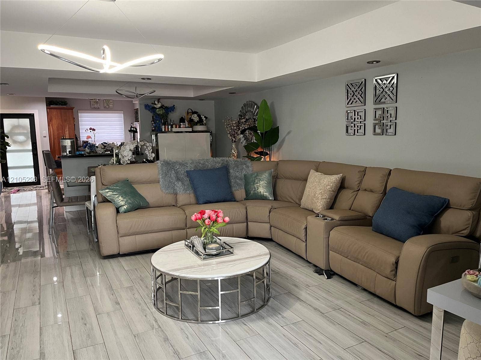 3792 NE 167th Street, #50, North Miami Beach, FL 33160 Open-concept interior featuring wood-finish tile flooring, recessed ceiling lighting, a modern geometric pendant light fixture, and crown molding