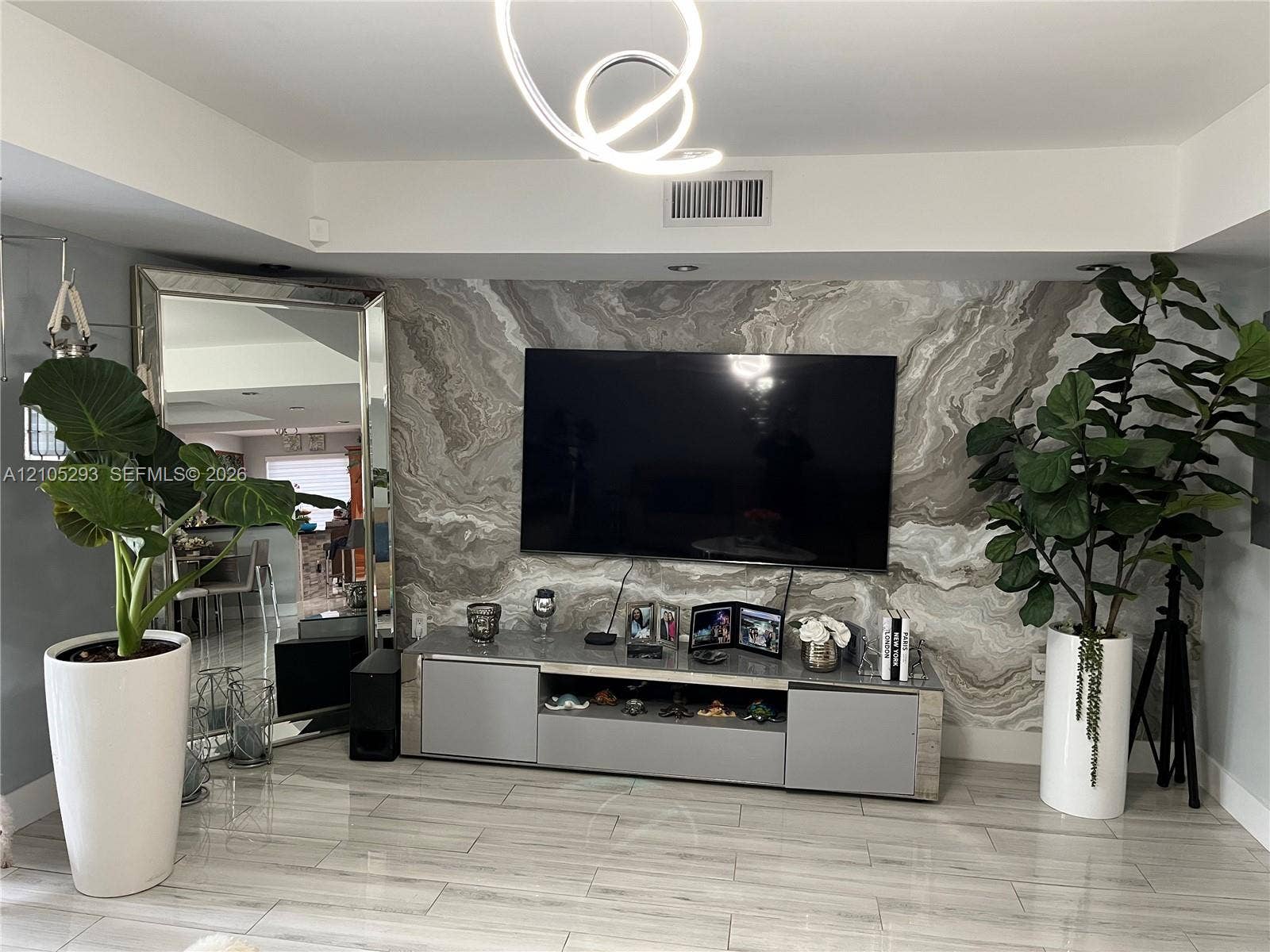 3792 NE 167th Street, #50, North Miami Beach, FL 33160 Stone-clad accent wall with organic patterning, light-toned tile flooring, and custom sculptural LED ceiling light fixture