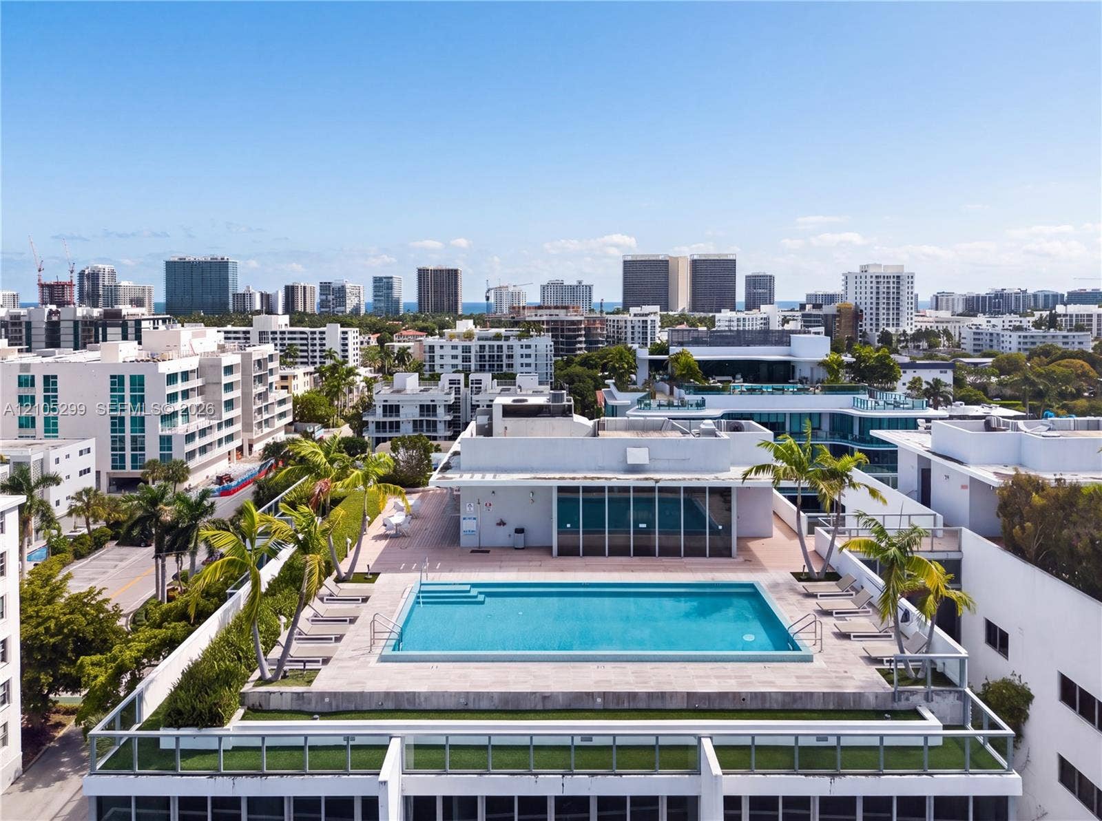Rooftop swimming pool with surrounding deck space, integrated planters, and distant cityscape