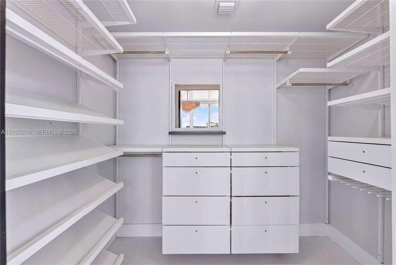 Integrated closet system with extensive shelving, built-in drawer units, hanging rods, and an overhead window