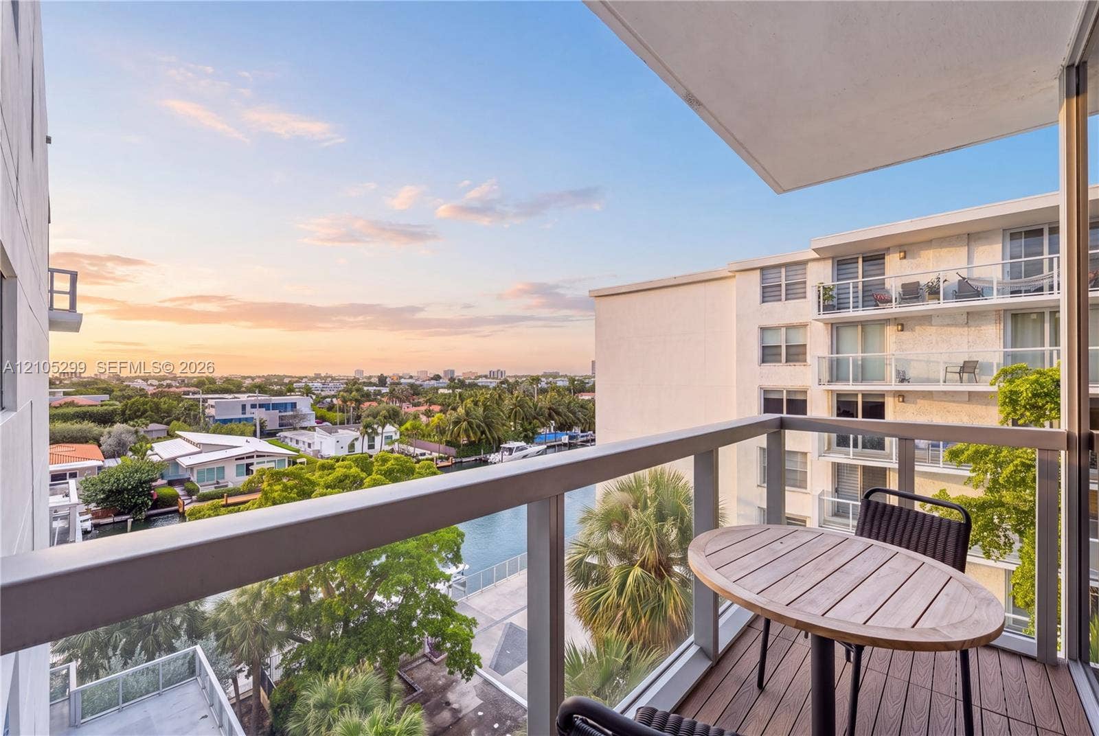 Balcony featuring a wood-finish deck, glass and metal railing, and high-rise building architecture