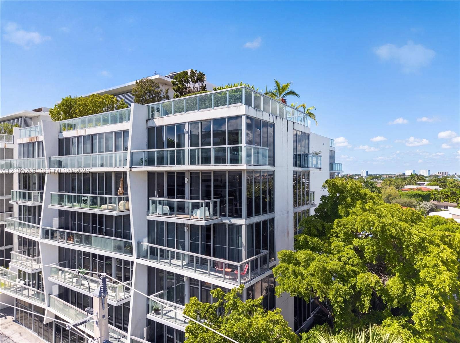 Modern high-rise with multiple levels of balconies, glass railings, and expansive windows