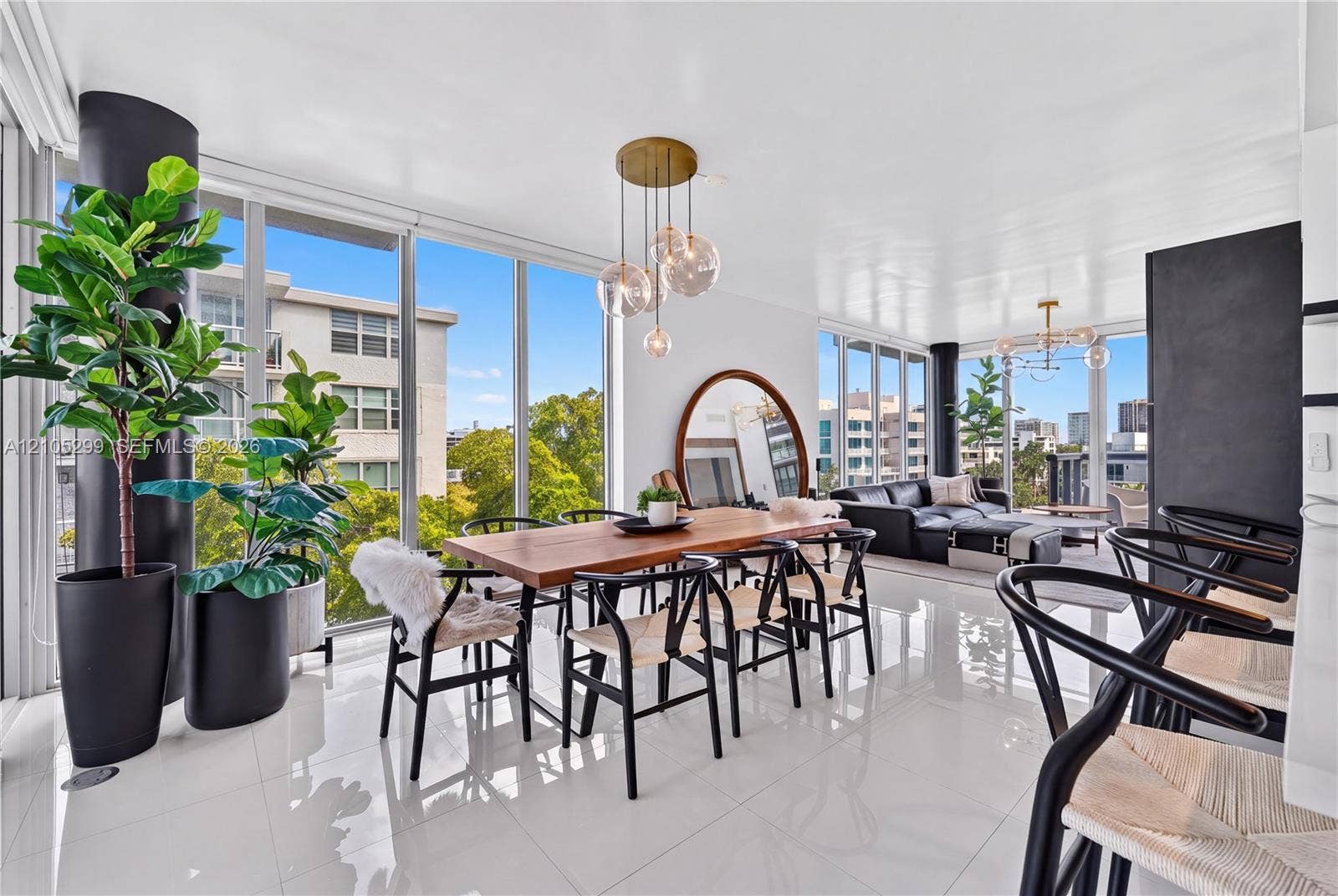 Expansive living space with white tile flooring, floor-to-ceiling windows, and a multi-light pendant fixture