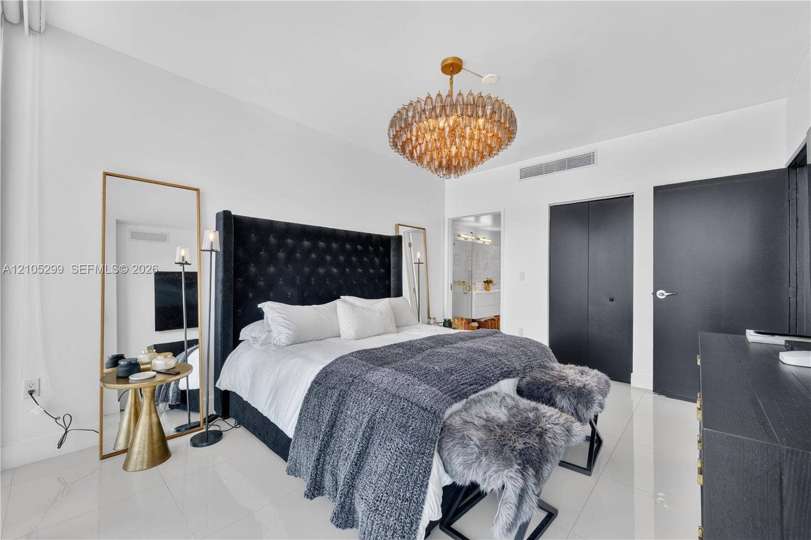 White tile flooring, modern chandelier, dark-toned doors, built-in air conditioning vent
