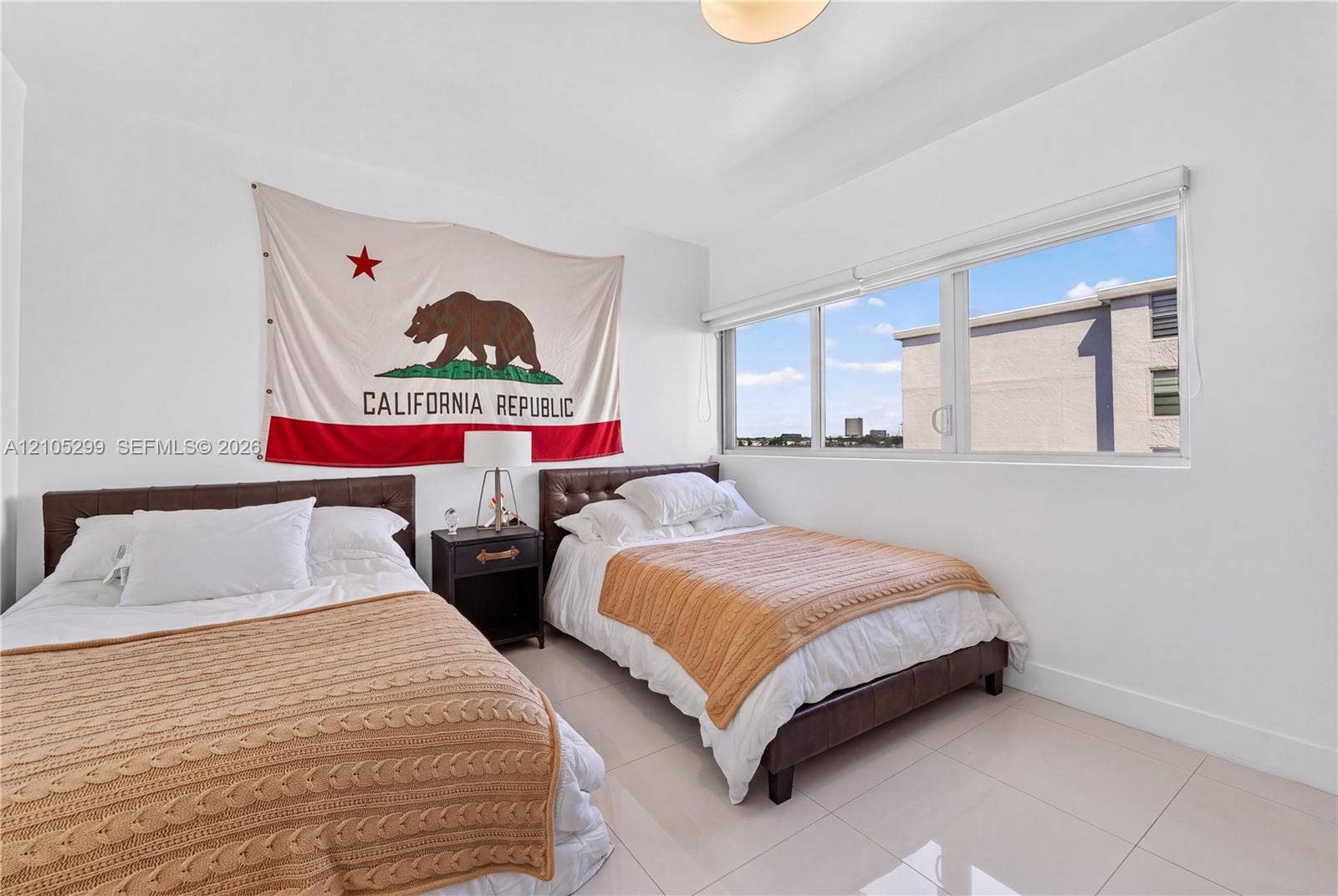 Recessed lighting, large window with roller shades, white walls, and tile flooring