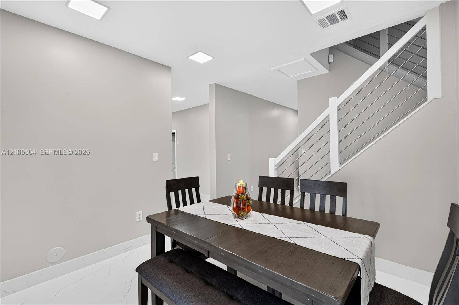 15217 SW 36th Terrace, Miami, FL 33185 Interior space featuring large-format tile flooring, recessed ceiling lighting, and a staircase with a white handrail and horizontal metal cable railing