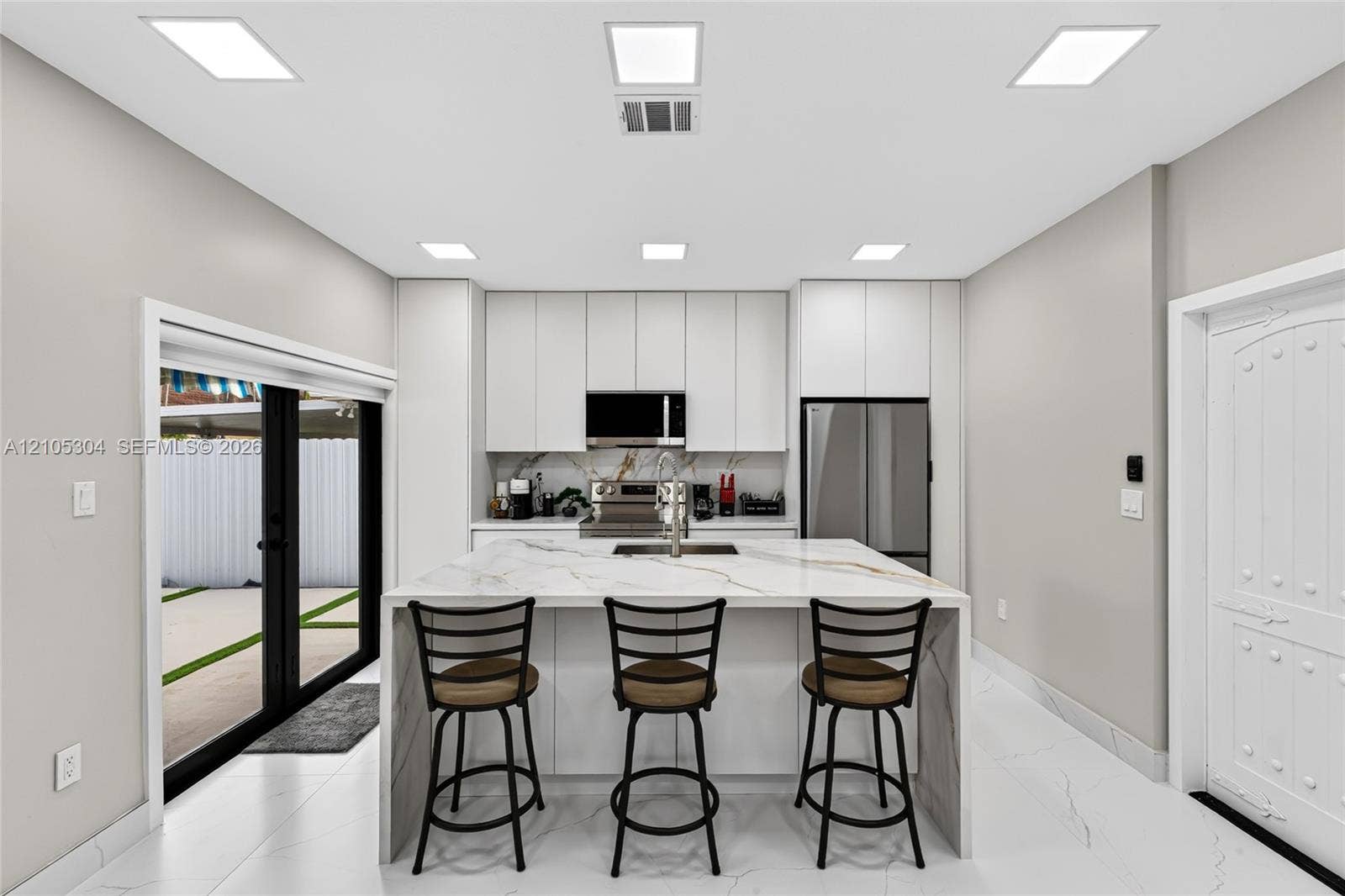 15217 SW 36th Terrace, Miami, FL 33185 Kitchen featuring floor-to-ceiling cabinetry, a central island with a waterfall-edge countertop, stainless steel appliances, recessed lighting, and large-format tile flooring