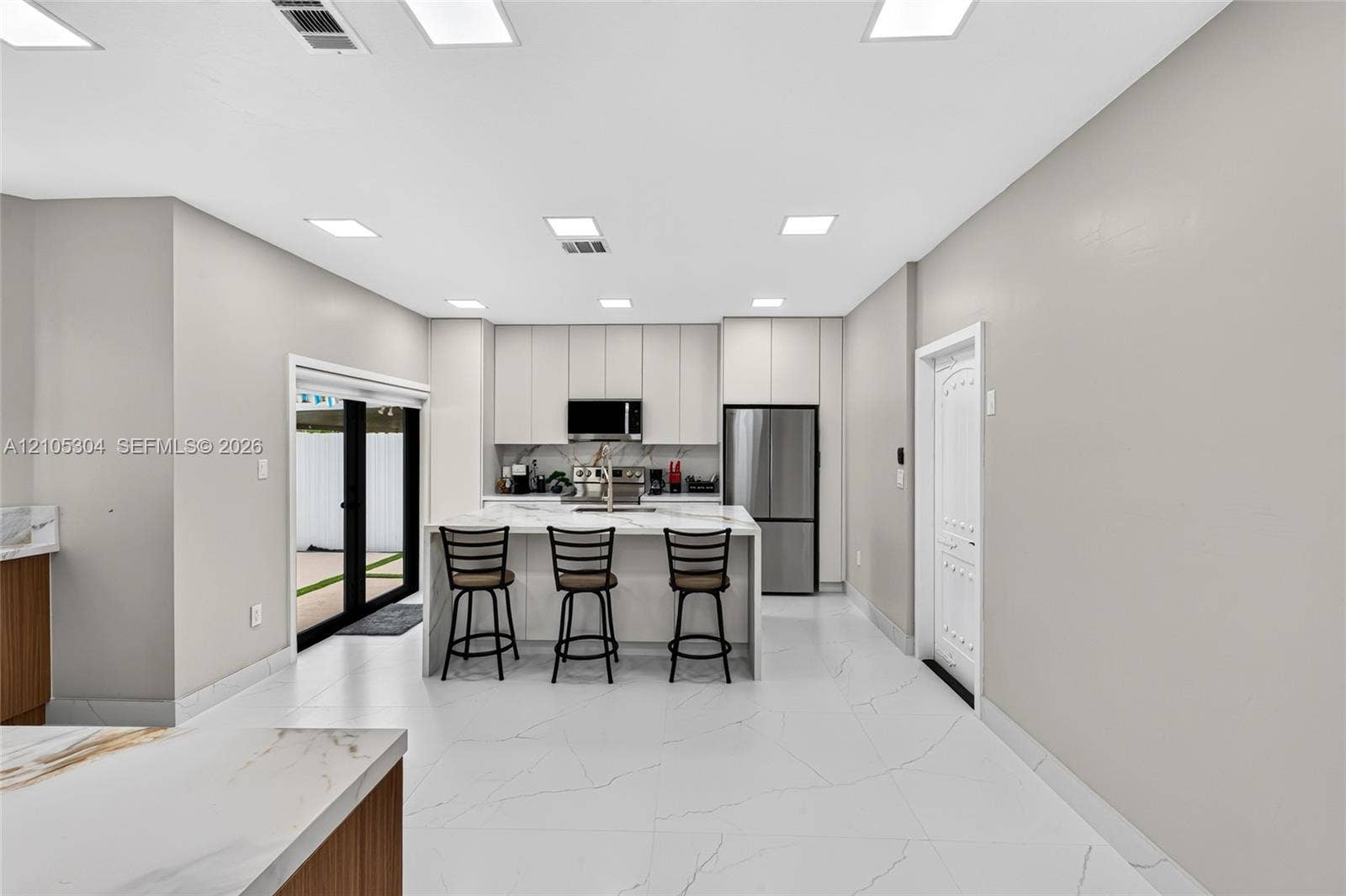 15217 SW 36th Terrace, Miami, FL 33185 Kitchen featuring floor-to-ceiling cabinetry, a central island with a stone-surface countertop, stainless steel appliances, and large-format tile flooring with recessed lighting