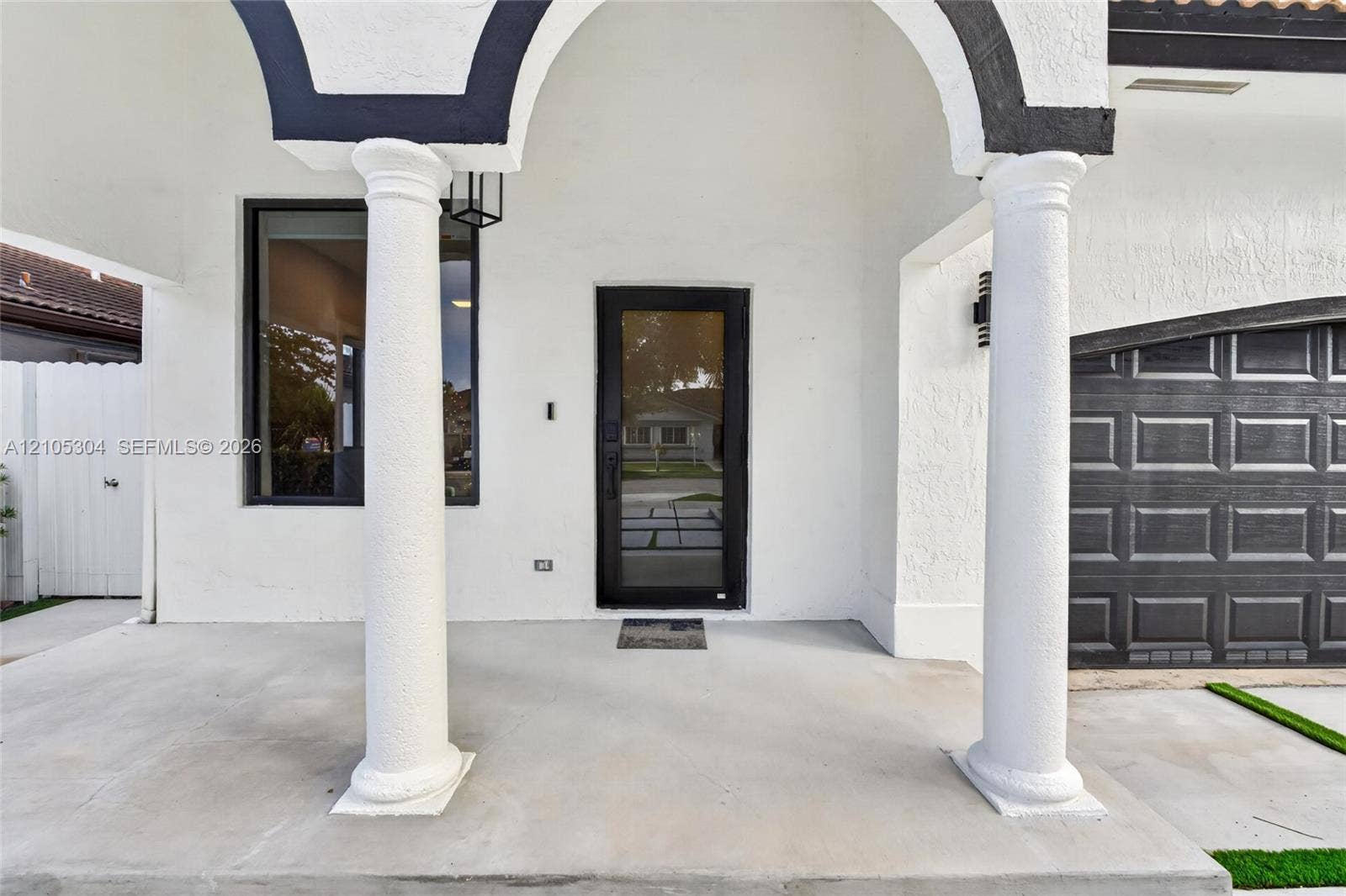 15217 SW 36th Terrace, Miami, FL 33185 Covered entryway featuring structural columns, stucco exterior finish, full-glass front door, and paneled garage door