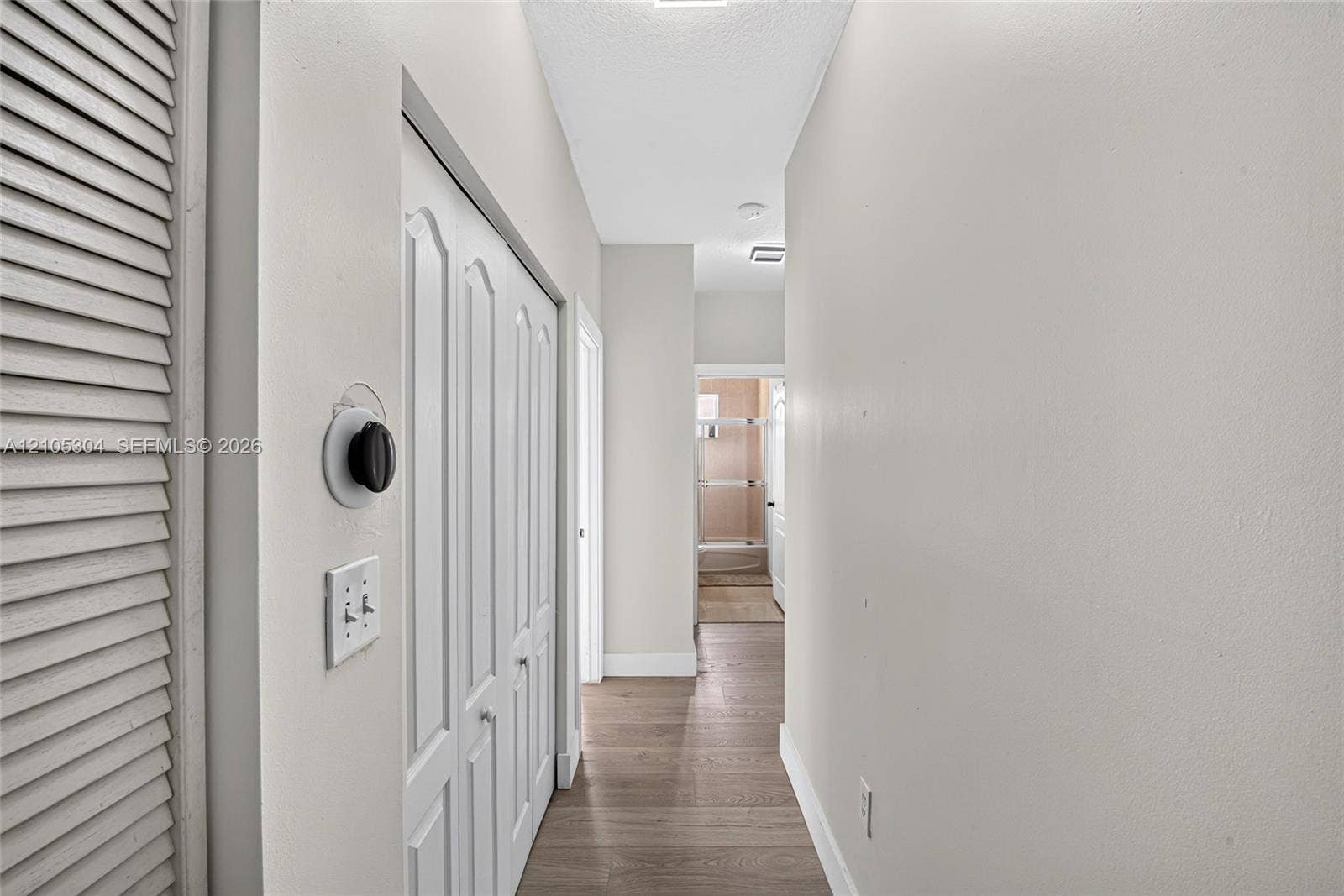 15217 SW 36th Terrace, Miami, FL 33185 Hallway featuring wood-finish flooring, white louvered closet doors, and a double-panel interior closet door