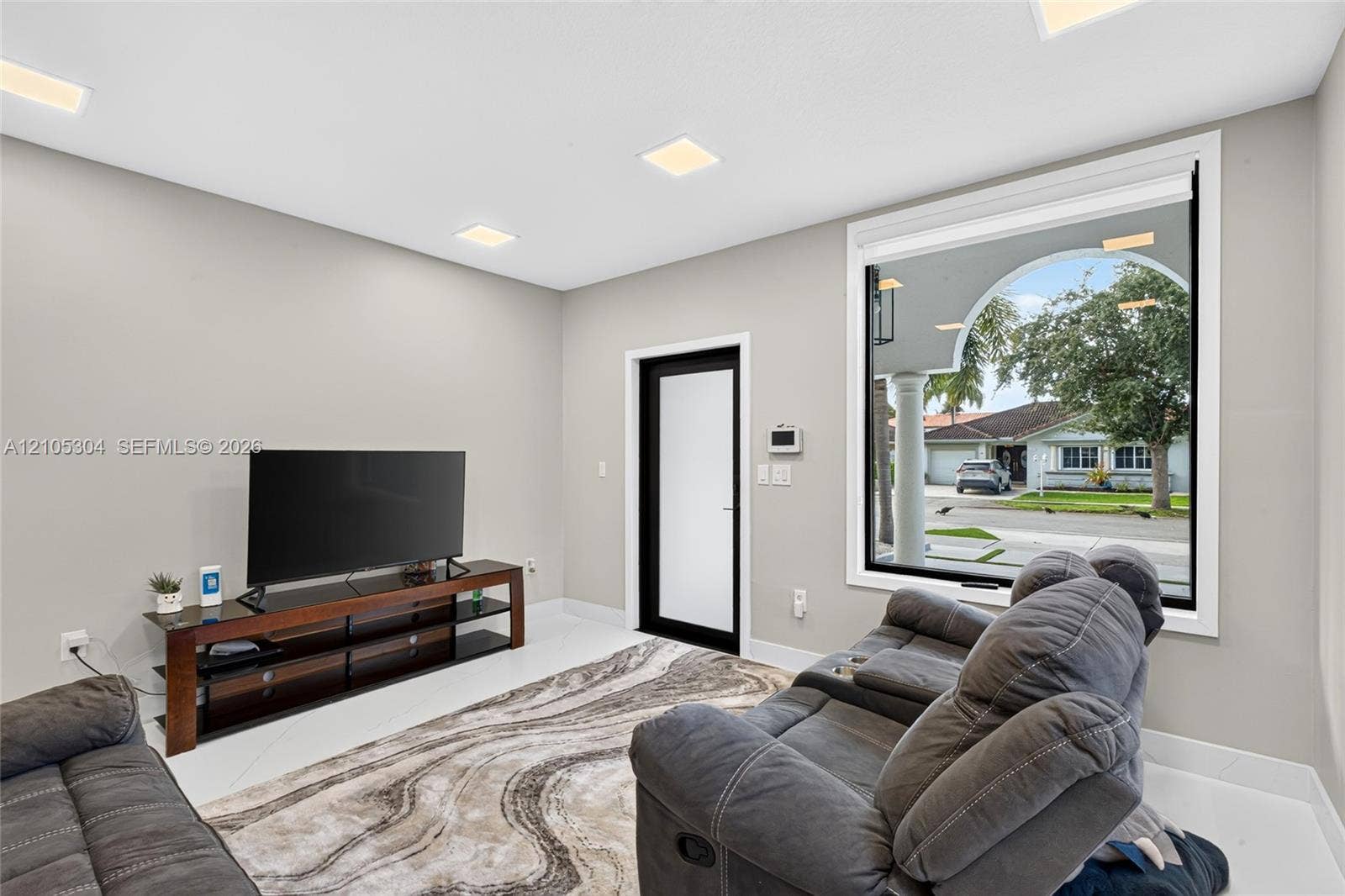 15217 SW 36th Terrace, Miami, FL 33185 Interior space featuring recessed lighting, smooth-finish walls, large-format tile flooring, a glass-panel door with a black frame, and a wide-format window