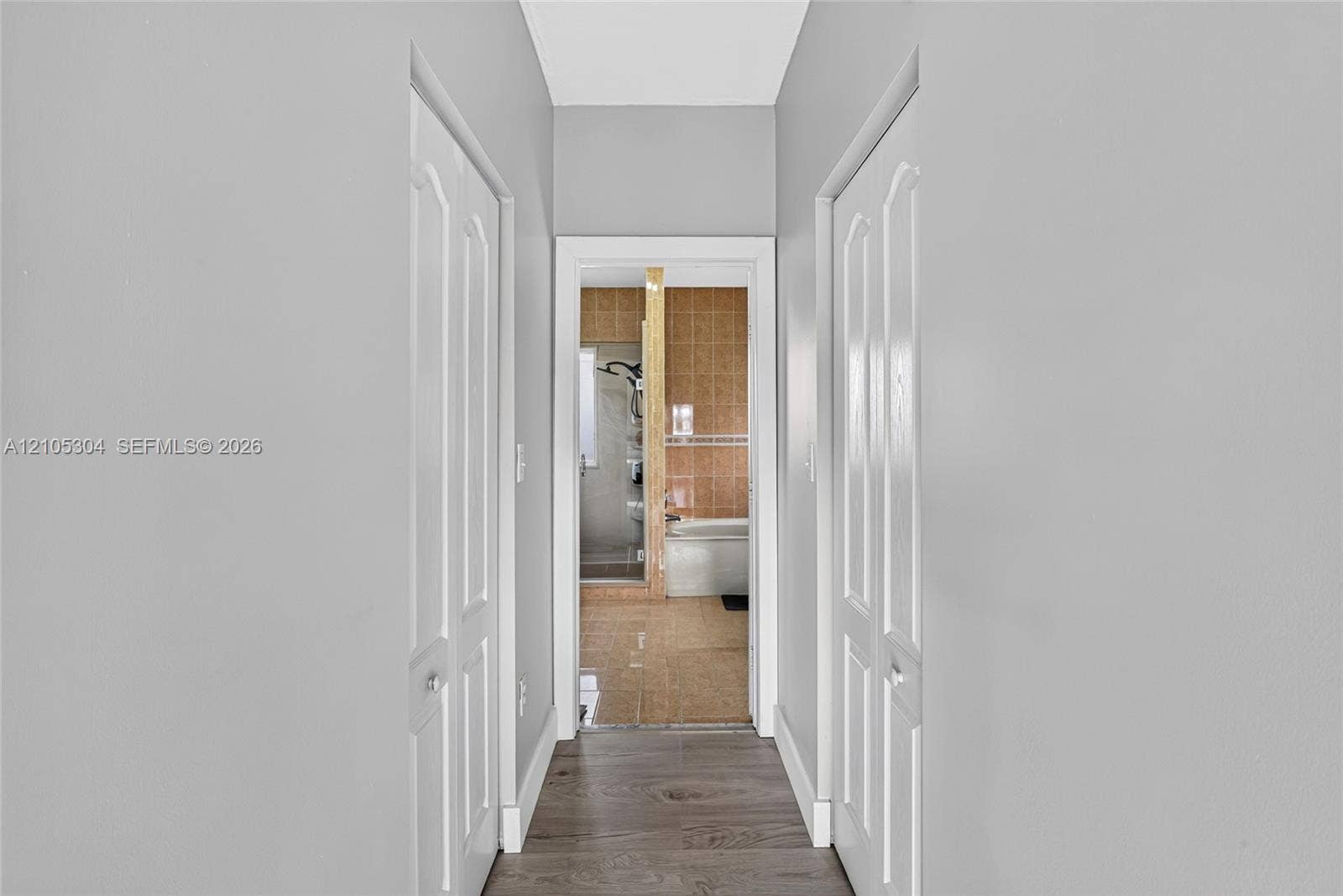 15217 SW 36th Terrace, Miami, FL 33185 Hallway featuring wood-finish flooring and two sets of arched-panel bi-fold doors