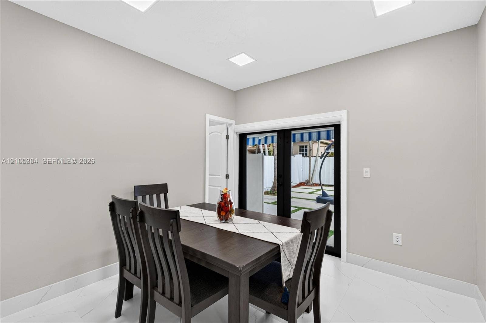 15217 SW 36th Terrace, Miami, FL 33185 Interior space featuring large-format tile flooring, recessed ceiling lighting, and black-framed French doors with exterior access