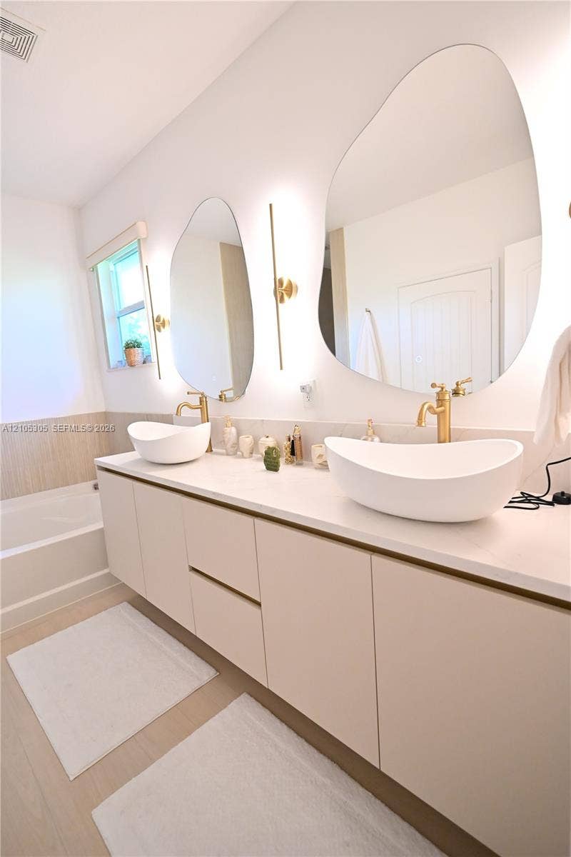 Floating vanity with dual vessel sinks, wall-mounted fixtures, and integrated lighting