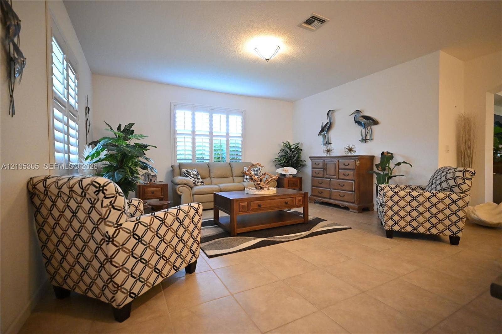 Tiled flooring, white wall paint, two windows with plantation shutters, vaulted ceiling, and a flush mount light fixture