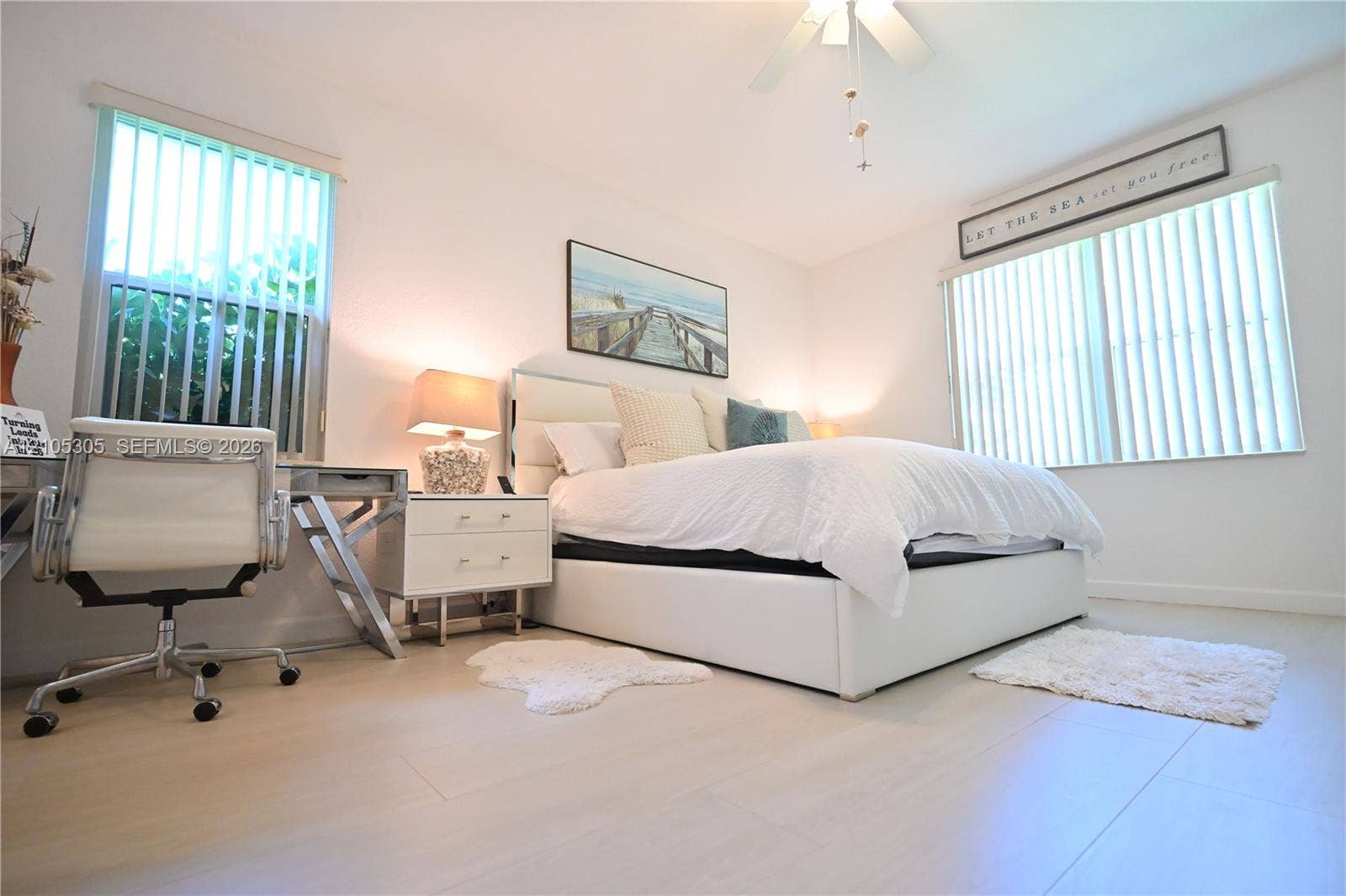 Light wood-finish flooring, white walls, and a ceiling fan with light fixture