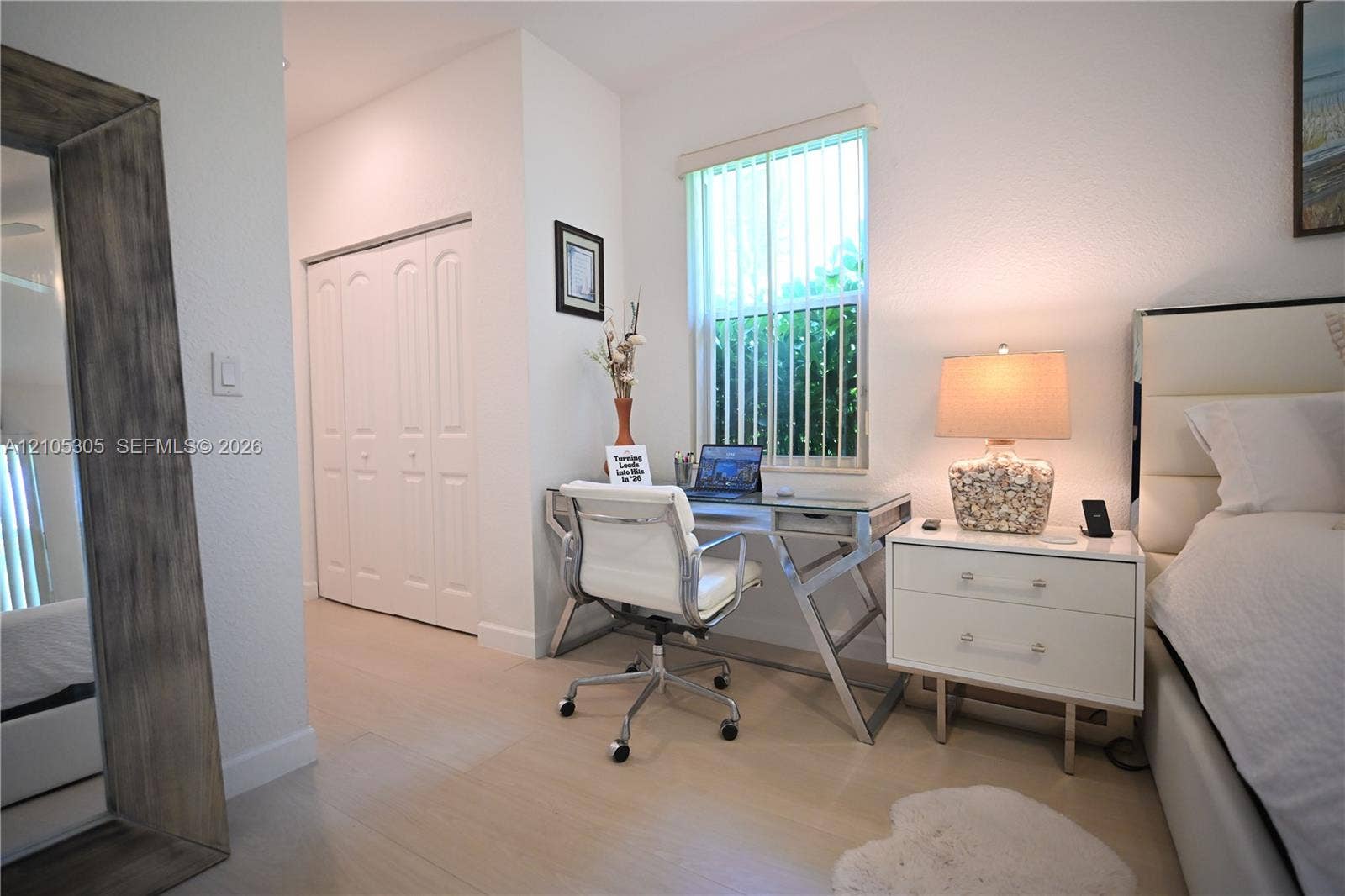Wood-finish flooring throughout, featuring a window with vertical blinds, and a built-in closet with bifold doors
